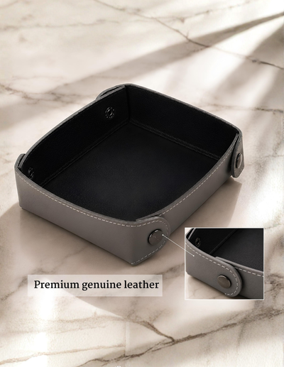 A square gray leather storage box with a black interior, shown on a light marble surface with a close-up inset of the leather edge and text reading 'Premium genuine leather'.