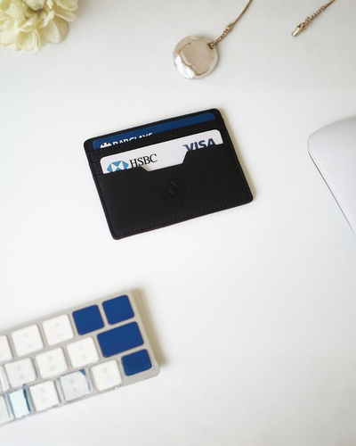 A black leather cardholder wallet with a white HSBC visa card partially inserted, shown against a plain white background.