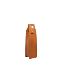 A tall, slim tan leather bag with a structured rectangular body, a top handle cutout, and a small leather tab with a silver snap closure, shown on a plain white background.