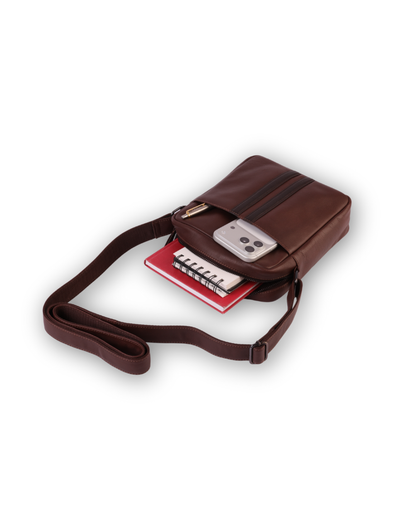 A brown leather crossbody phone bag with a matching adjustable strap, shown with a smartphone and notebook tucked into its interior compartments against a plain white background.