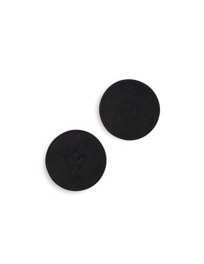 Two round black silicone earplugs with a subtle embossed geometric logo, displayed on a clean white background.