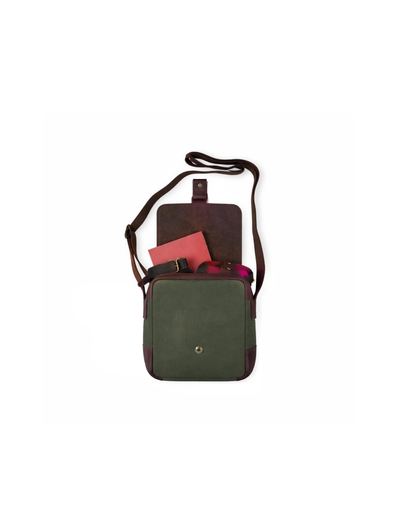A dark green and dark brown crossbody bag with a small front pocket, shown on a plain white background with a pink notebook peeking out of the top pocket.
