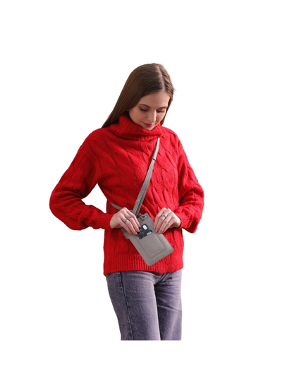 A woman wearing a bright red cable-knit mock neck sweater and gray jeans, shown from the waist up. She is holding a small gray crossbody wallet bag with a gray strap.