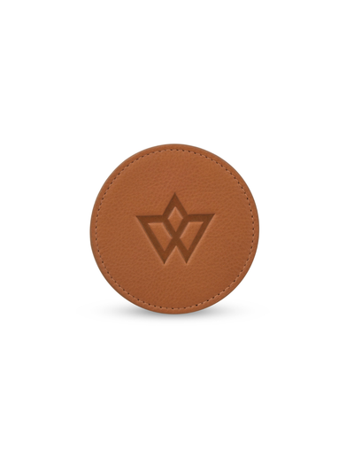 A round brown leather accessory with a debossed geometric logo in the center, shown on a clean white background.