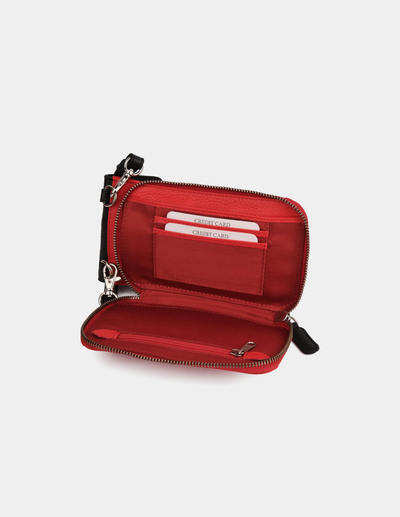 A red zip-around wallet shown open against a light gray background, featuring card slots, a wristlet strap, and silver-tone hardware.