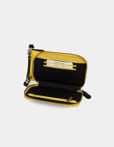 An open zip-around wallet in yellow black, showing interior card slots and a wristlet strap, photographed on a plain light gray background.